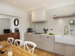 uma cozinha com uma mesa, um lavatório e um balcão em Tri Raglan Mawr em Beaumaris