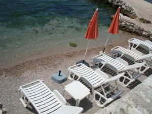 un grupo de sillas de césped y una sombrilla en una playa en Villa Perla Del Mare, en Kotor