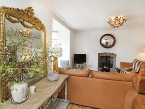 a living room with a couch and a mirror at Tri Raglan Mawr in Beaumaris