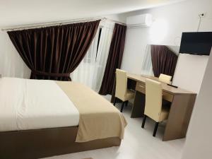 オトペニにあるFAST Airport Accomodationのベッドとデスクが備わるホテルルームです。