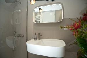 ein Badezimmer mit einem weißen Waschbecken und einem Spiegel in der Unterkunft Eftopia Beachfront Studio in Kokkari