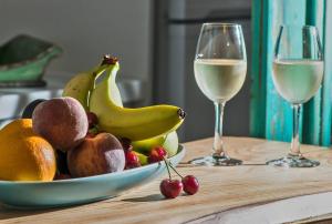 eine Schale Obst auf einem Tisch mit zwei Gläsern Wein in der Unterkunft Eftopia Beachfront Studio in Kokkari