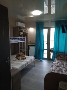 a room with two beds and a kitchen with blue curtains at La Kosta Zatoka in Zatoka