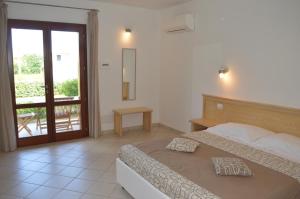 Schlafzimmer mit einem Bett und einer Tür zu einem Balkon in der Unterkunft Guest Rooms Affittacamere in San Teodoro