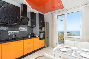eine Küche mit orangefarbenen Schränken und einem Tisch in der Unterkunft Barkar ArCadia Apartments in Odessa