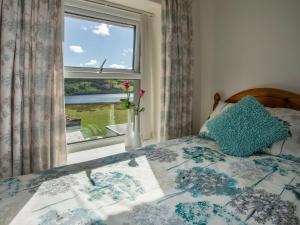 a bedroom with a bed with a window and a vase with flowers at 17 Victoria Terrace - Perthi in Nantlle