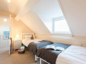 a attic bedroom with two beds and a window at West View in Rhosneigr