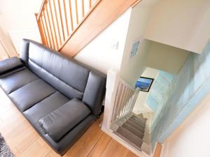 un sofá de cuero en una sala de estar con una escalera en Y Stabl, en Criccieth