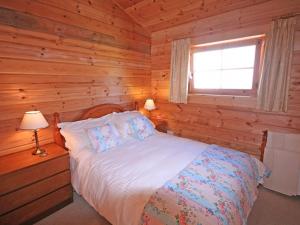 a bedroom with a bed in a log cabin at Y Berllan in Bodorgan
