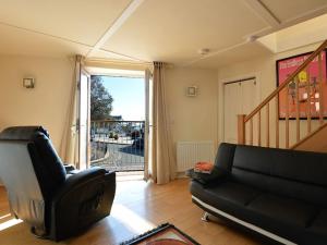 ein Wohnzimmer mit einem schwarzen Sofa und einem Stuhl in der Unterkunft Y Stabl in Criccieth