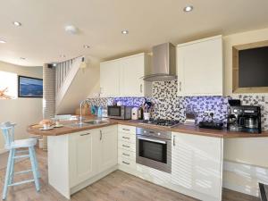 a kitchen with white cabinets and a counter top at Y Stabl in Criccieth