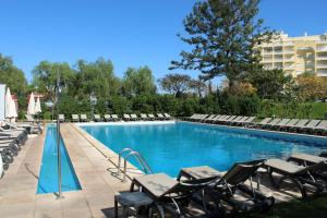 uma piscina com espreguiçadeiras e um hotel em Luna Olympus em Vilamoura