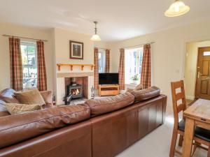 a brown leather couch in a living room with a fireplace at Gowanlea in Hexham