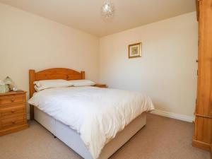 een slaapkamer met een wit bed en een houten dressoir bij The Cottage at Manor Farm in York