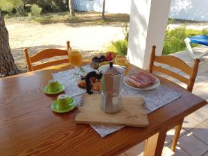 een houten tafel met twee glazen sinaasappelsap en eten bij Can Tauet de ses Roques in Playa Migjorn