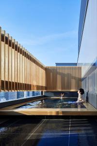 a woman sitting in a swimming pool in a building at ONSEN RYOKAN YUEN SHINJUKU in Tokyo