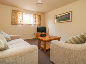 ein Wohnzimmer mit zwei Sofas und einem Fernseher in der Unterkunft The Cottage at Manor Farm in York