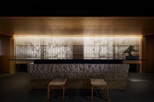 a lobby with two chairs and a bar with a plant at ONSEN RYOKAN YUEN SHINJUKU in Tokyo