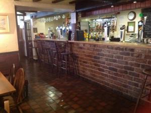 a bar in a restaurant with a brick wall at The New Inn in Oswestry