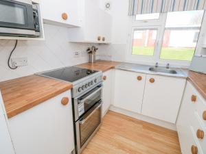 a kitchen with white cabinets and a stove and a sink at The Borrowers in Dartmouth