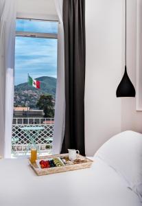 a tray of food sitting on a bed next to a window at La Spezia by The First - Luxury Rooms & Suites in La Spezia