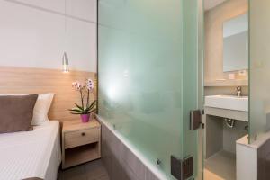 a bathroom with a shower and a bed and a sink at Princess Golden Beach Hotel in Chrysi Ammoudia