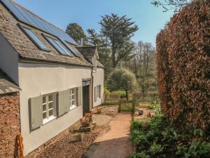 a white house with green windows and a yard at Upper Barn Cottage in Minehead