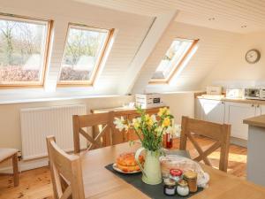 a kitchen with a table with a vase of flowers on it at Upper Barn Cottage in Minehead