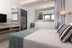 a hotel room with a bed and a television at Princess Golden Beach Hotel in Chrysi Ammoudia