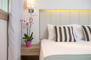 a bedroom with a bed and a vase with pink flowers at Princess Golden Beach Hotel in Chrysi Ammoudia