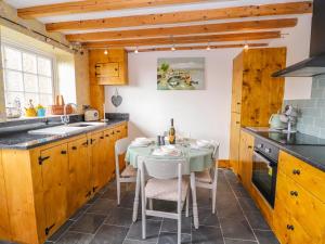 una cucina con tavolo, sedie e lavandino di Woodland Cottage a Llangollen