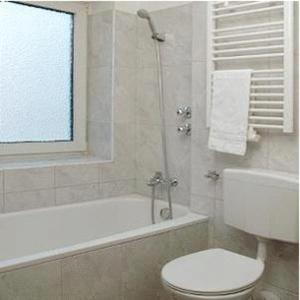 a bathroom with a toilet and a bath tub with a window at City Hotel Mercator in Frankfurt/Main +33 photos