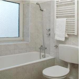 a bathroom with a toilet and a bath tub with a window at City Hotel Mercator in Frankfurt