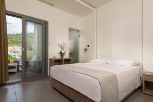a white bedroom with a bed and a balcony at Princess Golden Beach Hotel in Chrysi Ammoudia