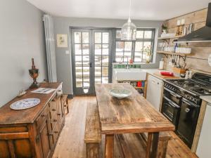 a kitchen with a wooden table and a stove at Fountain View Cottage in Upper Heyford
