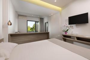 a bedroom with a white bed and a flat screen tv at Princess Golden Beach Hotel in Chrysi Ammoudia