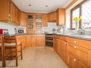 a large kitchen with wooden cabinets and a sink at Chiffchaff in Padstow
