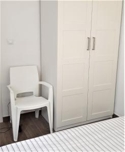 Una silla blanca en una habitación con armario en Immaculada Apartament Gandia, en Gandía