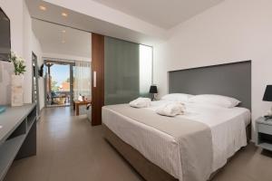 a bedroom with a large bed with white sheets at Princess Golden Beach Hotel in Chrysi Ammoudia