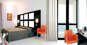 1 dormitorio con 1 cama, sillas de color naranja y escritorio en Hotel Admeto, en Marinella di Selinunte