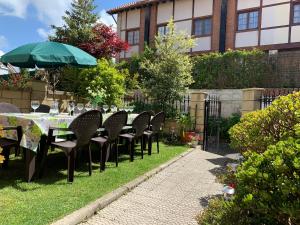a table with chairs and an umbrella in a garden at "LAS CAMELIAS SOMO" un lugar para desconectar!! Vistas al MAR!! in Somo