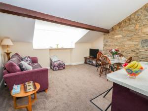 sala de estar con sofá púrpura y pared de piedra en Tram View, en Llandudno