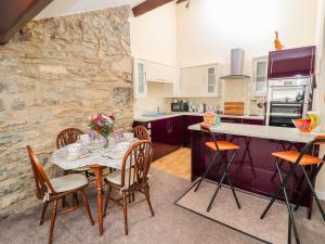 cocina con mesa, sillas y pared de piedra en Tram View, en Llandudno