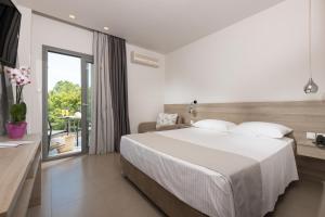 a bedroom with a large bed and a balcony at Princess Golden Beach Hotel in Chrysi Ammoudia