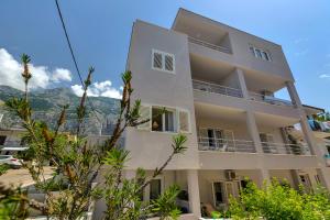 a white apartment building with mountains in the background at Apartman Jug in Makarska