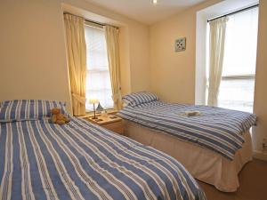 twee bedden in een slaapkamer met een teddybeer op een tafel bij Bwthyn Llechen in Porthmadog
