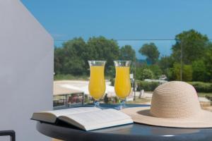two glasses of orange juice and a hat on a table at Princess Golden Beach Hotel in Chrysi Ammoudia