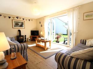 a living room with two couches and a tv at Bwthyn y Mor in Porthmadog