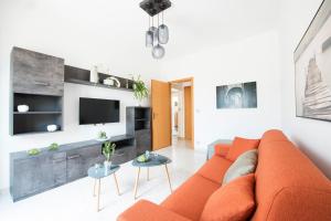 een woonkamer met een oranje bank en een tv bij Casa Vacanze La Meridiana in Modica