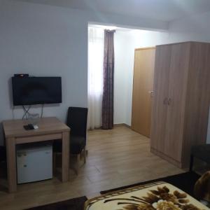 een woonkamer met een tafel, een televisie en een bureau bij Apartments Šofranac in Podgorica